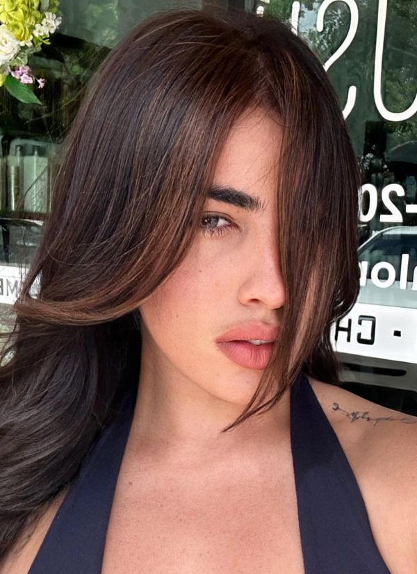 Close-up portrait of a woman with long brown hair partially covering her face.