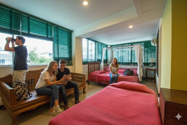 Four friends in a cozy hotel room with red bedding.