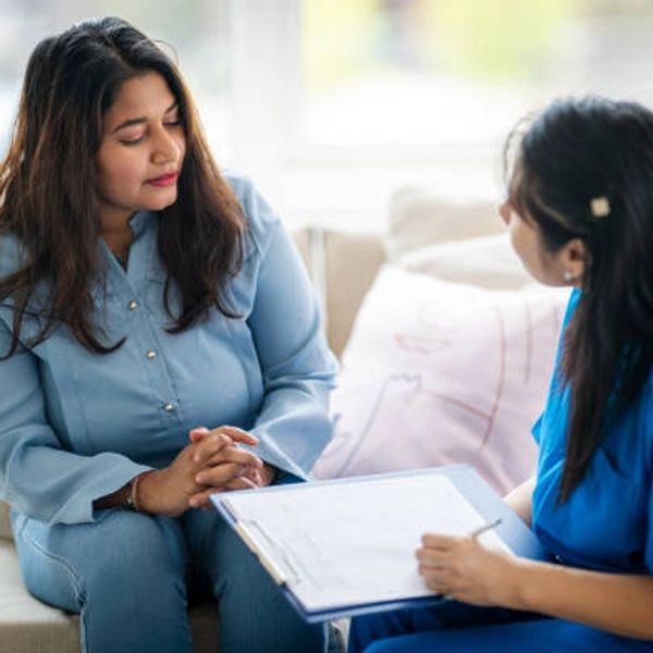 Two women engaged in a serious consultation, one holding a clipboard.