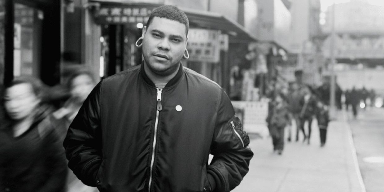 Man with stretched ear lobes stands on a busy city street in black and white.