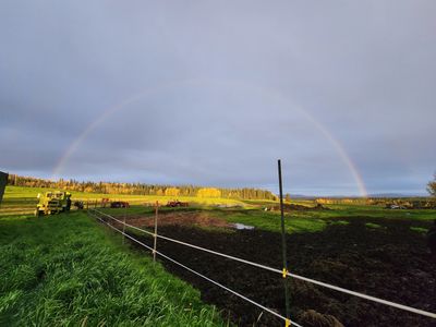 A full rainbow over a hay field.