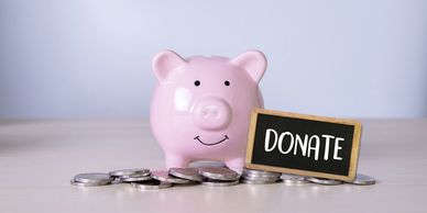 Pink piggy bank with coins and a donate sign.