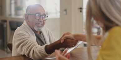 Two people shaking hands at a table.