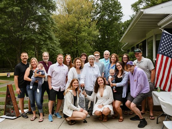 Large family gathering outdoors with multiple generations posing for a photo.