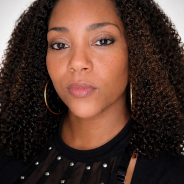 Close-up portrait of a woman with curly hair and hoop earrings.