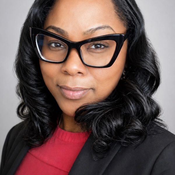 Confident woman wearing black glasses and a business outfit.