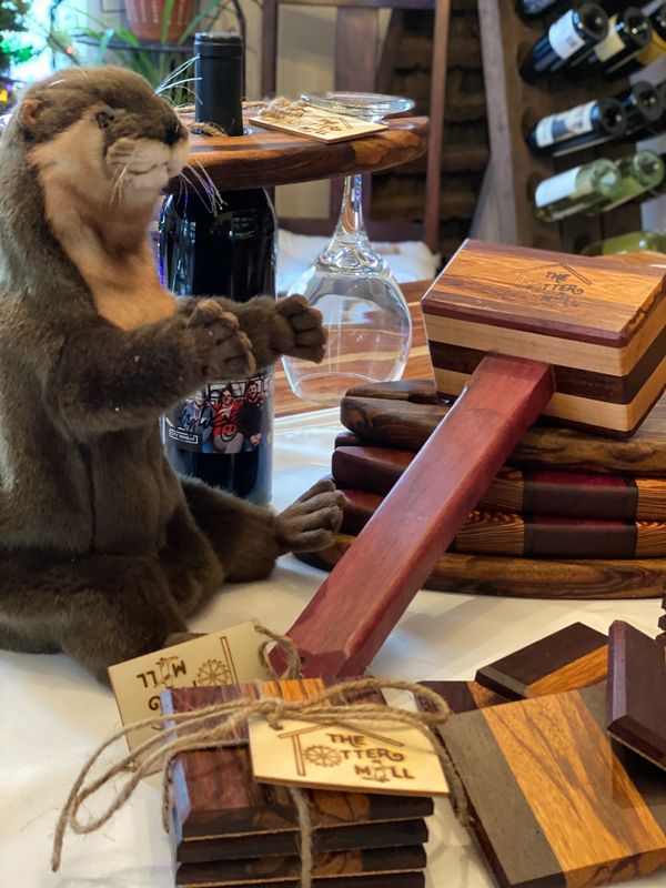 Stuffed otter toy next to wooden items and wine bottle at The Otter Mill.