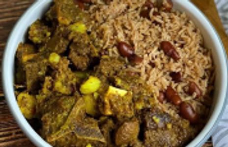 A bowl of curried goat with rice and peas.