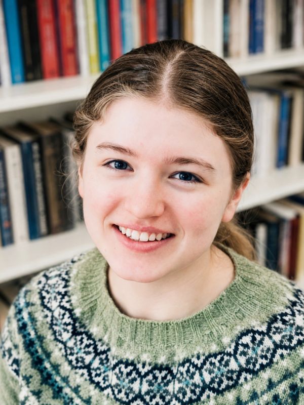 Smiling young woman in a patterned sweater.