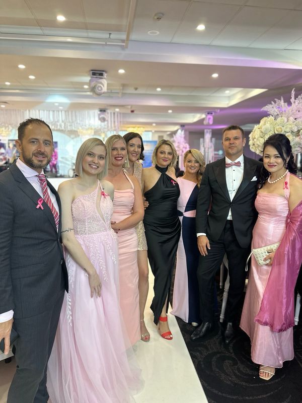 Group photo at a formal event with pink and black themed attire.