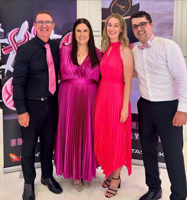 Four people dressed formally, smiling for a photo.