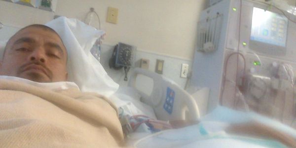 Man lying in hospital bed with medical equipment nearby.