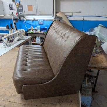 Brown tufted leather bench seat in workshop.