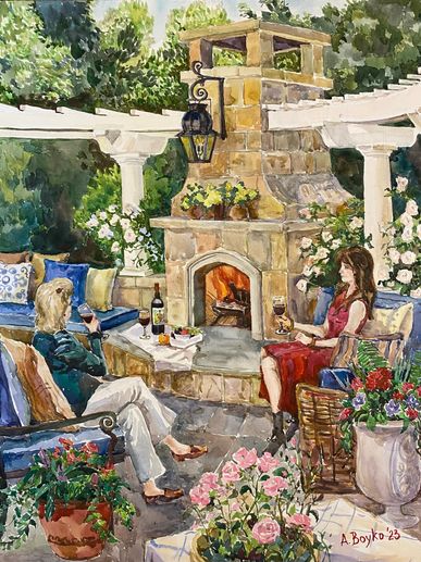 Two women enjoying drinks by an outdoor fireplace in a garden.