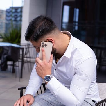 Man in white shirt talking on smartphone outdoors.