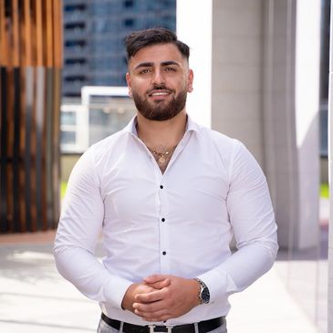 Confident man in a white shirt standing outdoors in an urban setting.