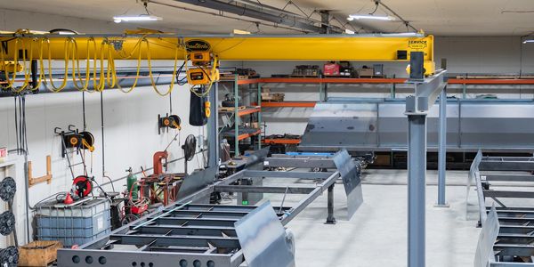Industrial workshop with metal frame structures and a yellow overhead crane.