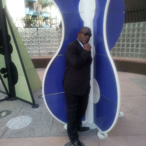 Man in a suit posing beside large musical note sculptures.