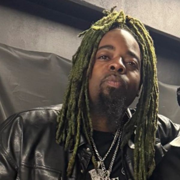 Man with green dreadlocks wearing a leather jacket.