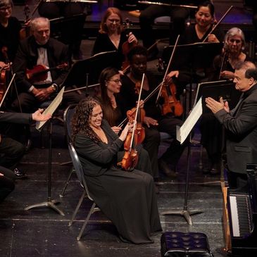 Musician smiling with violin during orchestra performance