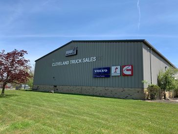 Cleveland Truck Sales building with Mack, Volvo, and Cummins logos under a clear blue sky.