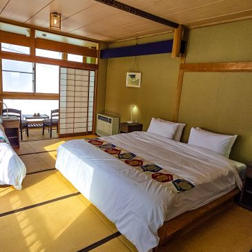 A cozy Japanese-style bedroom with tatami mats and a large bed.