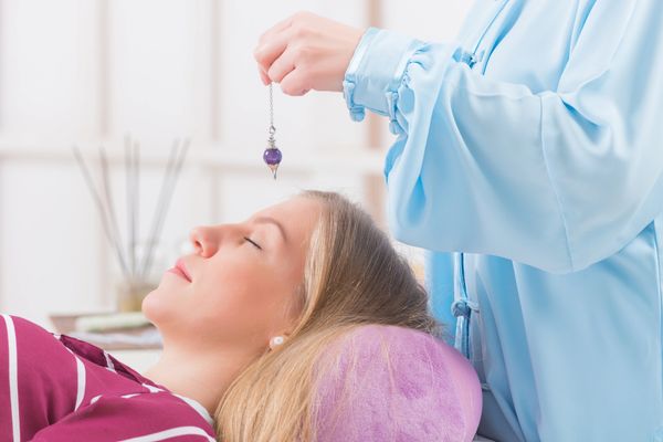 Practitioner using a pendulum for dowsing or hypnotherapy.