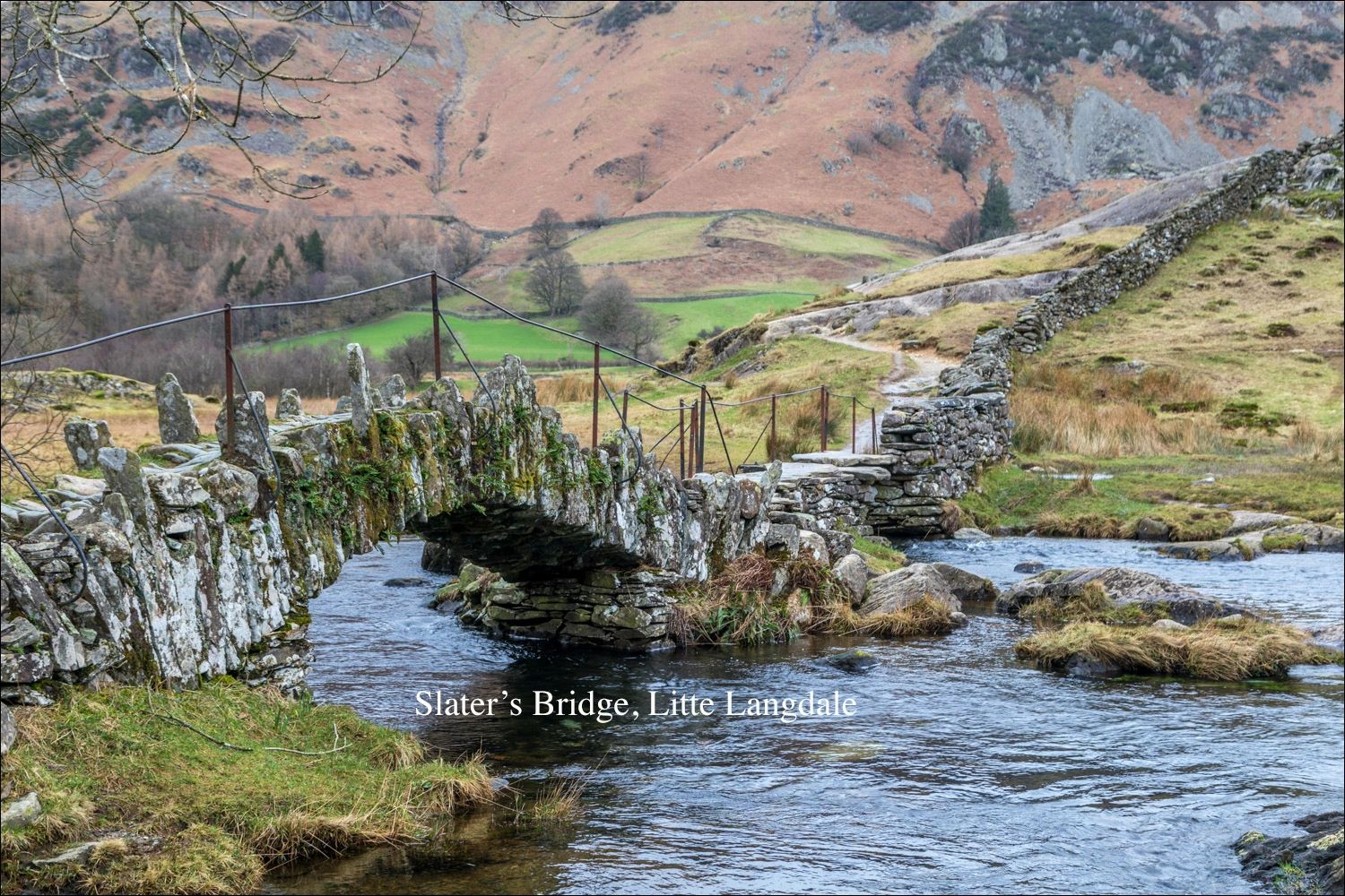 Ancient stone bridge crossing a stream in a scenic countryside.