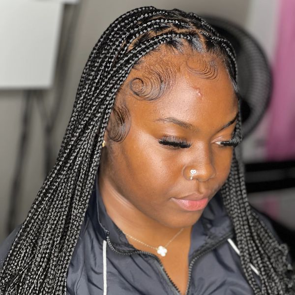 Woman with neat long box braids and styled baby hairs.