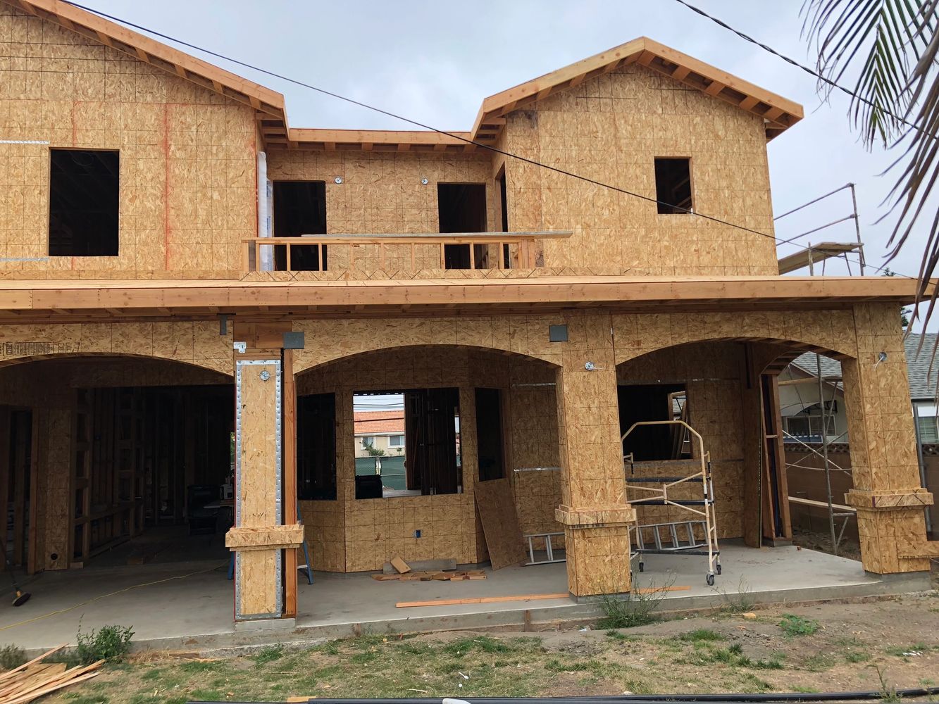 Two-story house under construction with wooden framework and arches.
