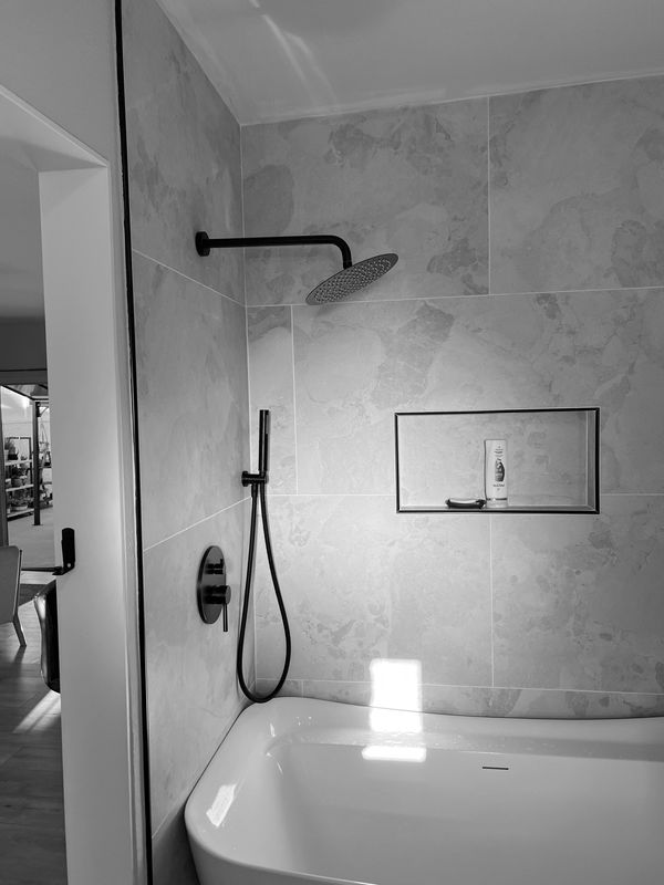 Modern bathroom with a bathtub and sleek black shower fixtures.