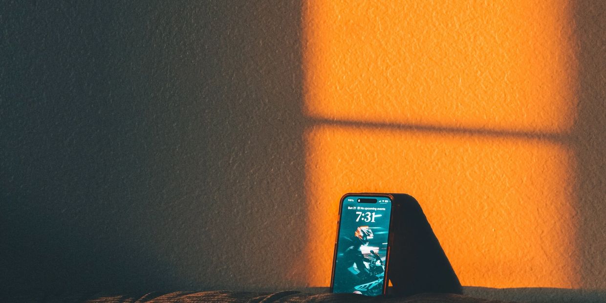 Phone displaying time with warm window light shadow.
