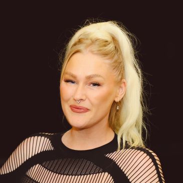 Smiling woman with blonde hair tied in a ponytail.