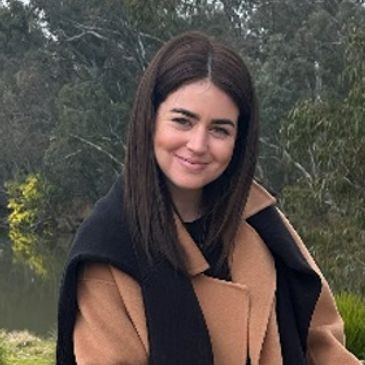 Young woman smiling outdoors near a river.