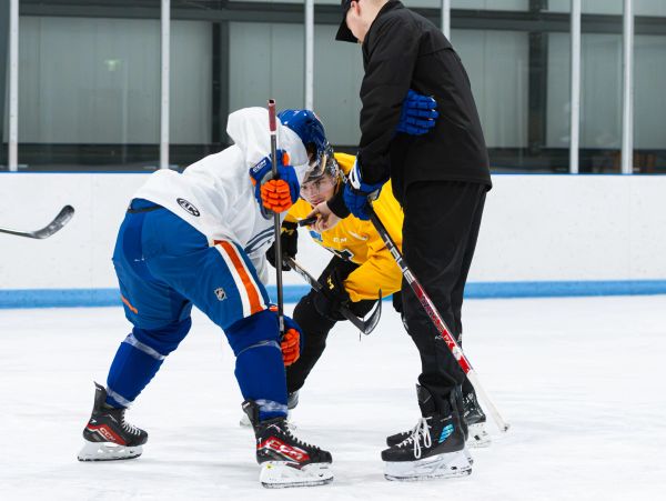 Three men preparing for a faceoff in ice hockey.