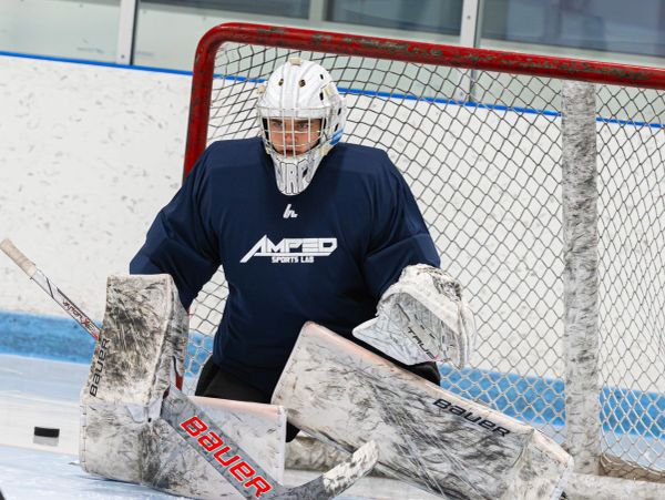 Ice hockey goalie in action, blocking a puck.
