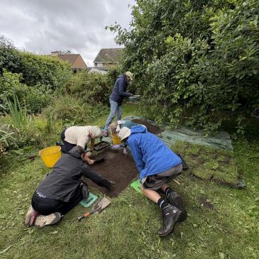 A group of volunteers digging aa test pit in a garden