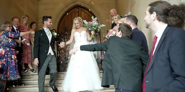 Bride and groom exit church, guests celebrate joyfully.