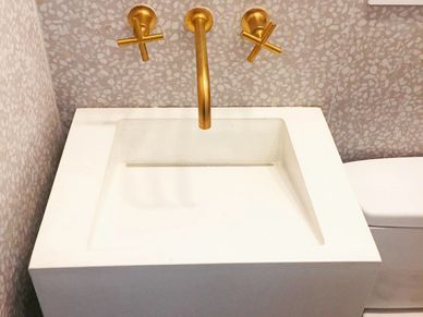 Modern bathroom sink with gold fixtures and white basin.