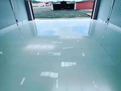 Empty, clean airplane hangar with shiny floor and open doors.