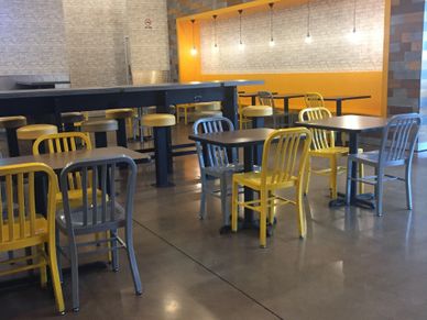 Empty modern cafeteria with yellow and gray chairs and pendant lights.