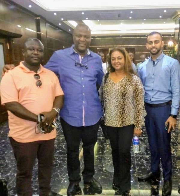 Four people posing together indoors in casual and business attire.