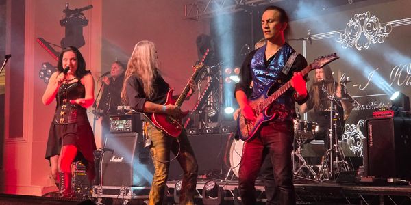A rock band performing live on stage with vibrant lighting.