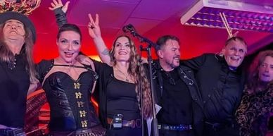 A joyful band celebrates on stage after a performance.