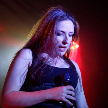Female singer performing passionately on stage with colorful lighting.