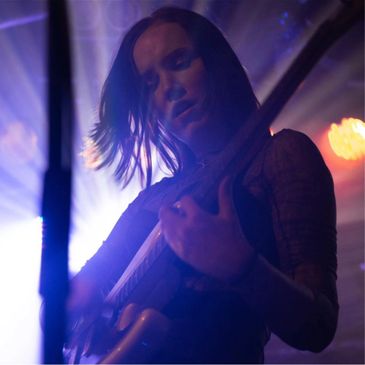 Female guitarist passionately playing on stage with dramatic lighting.