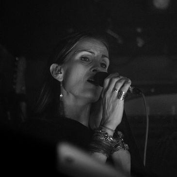 Black and white photo of a woman singing into a microphone.