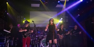 A band performs live on stage with colorful lighting effects.
