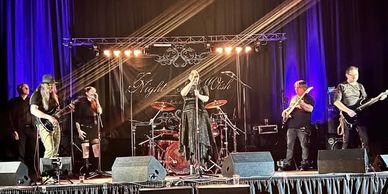 A band performs on stage under warm lights with a dark backdrop.
