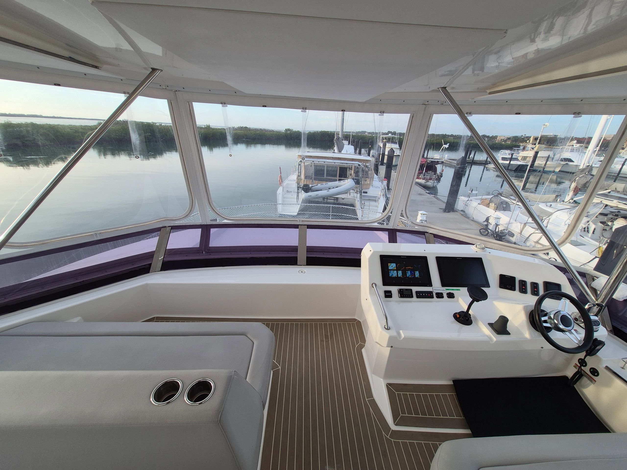 View from a yacht's helm showing a calm marina and docked boats.